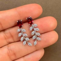 silver earrings gemstones with 5x7 mm oval garnet displayed on hand