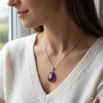 model wearing silver carved gemstone pendant with pear shaped african amethyst and cubic zirconia
