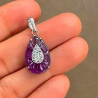 carved gemstone silver pendant with pear shaped african amethyst and cubic zirconia displayed on hand